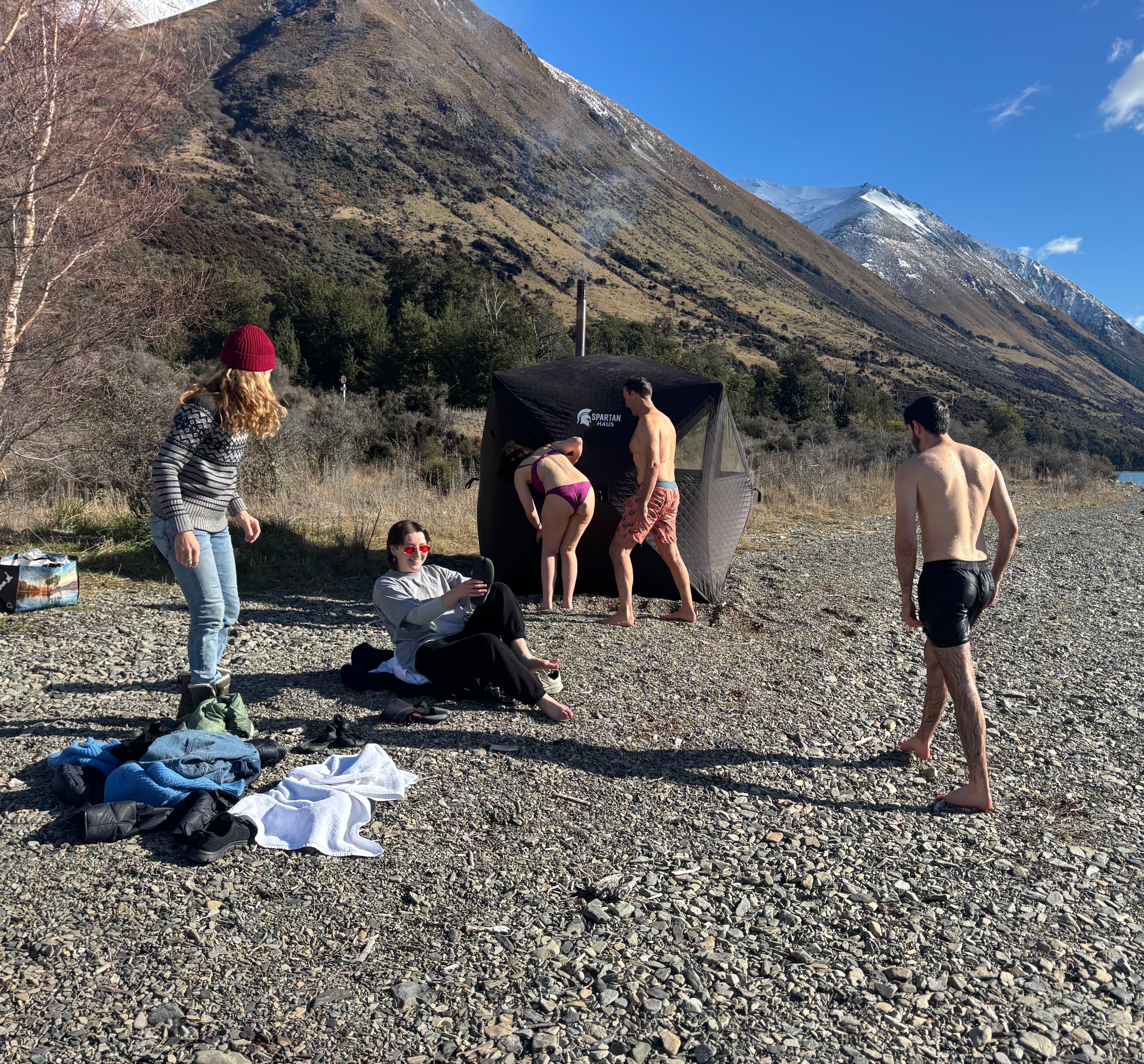 Group of people by a sauna tent in a mountainous area
